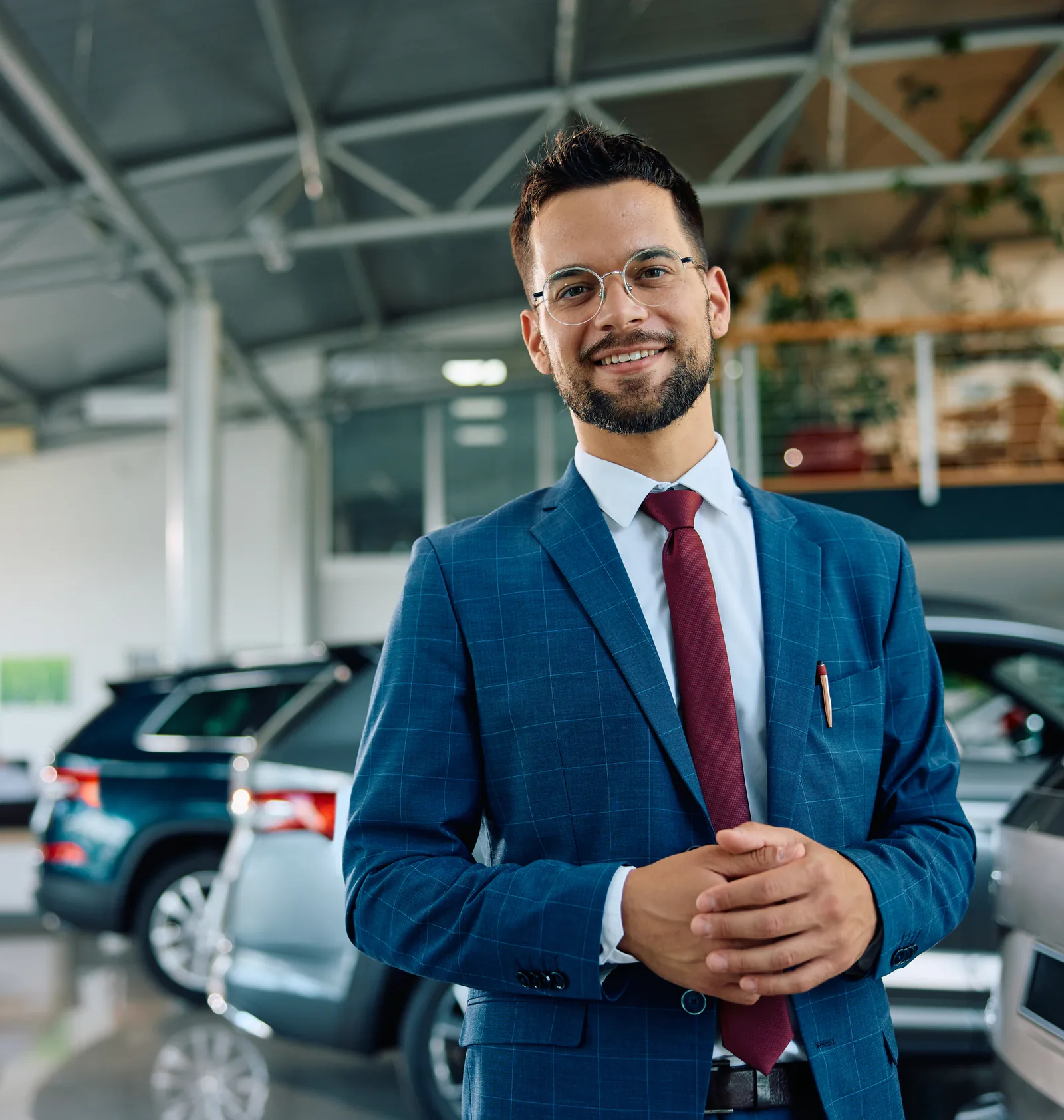 A car dealership manager in a suit standing on the showroom floor
