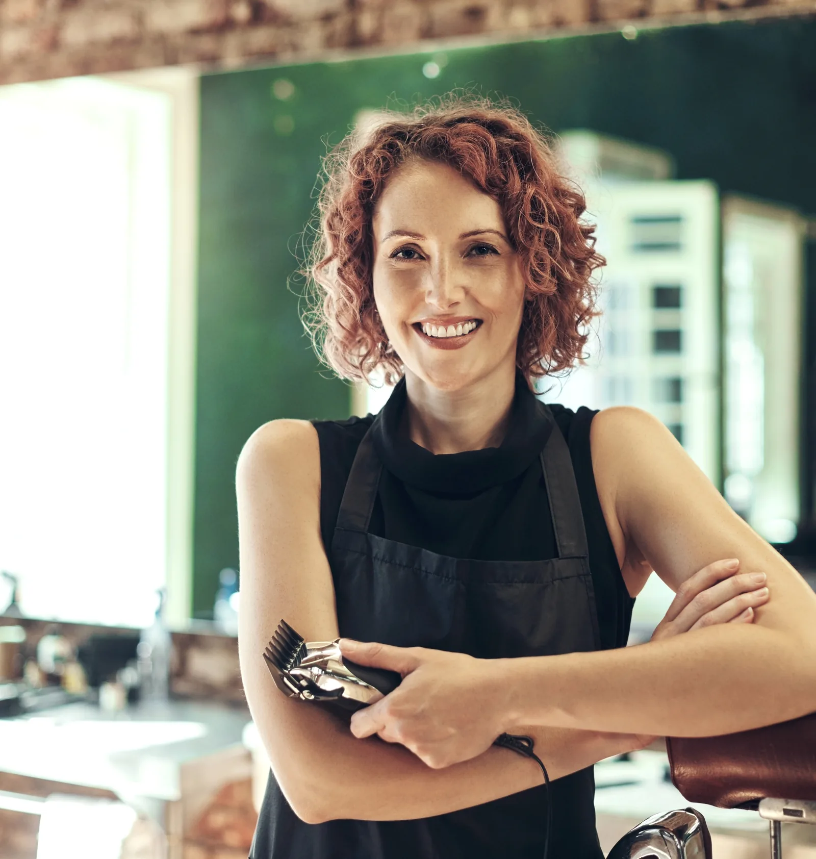 A hair salon owner holding clippers in her styling chair