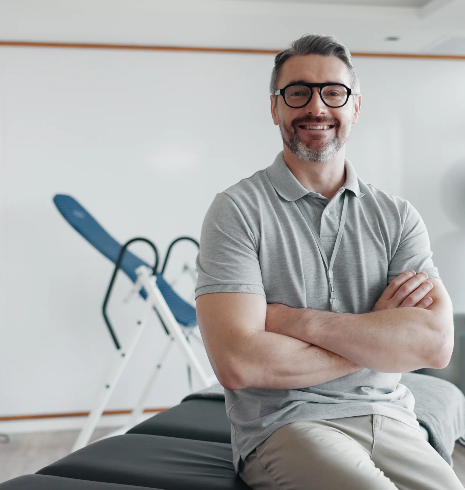A chiropractor sitting on a treatment table in his clinic