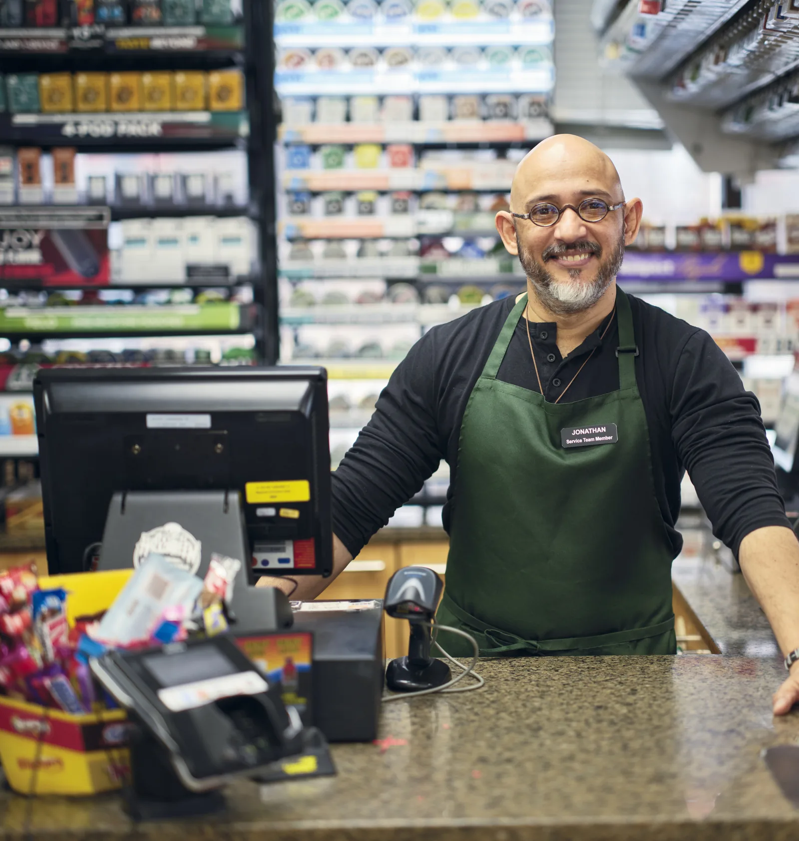 A convenience store clerk standing behind the checkout counter