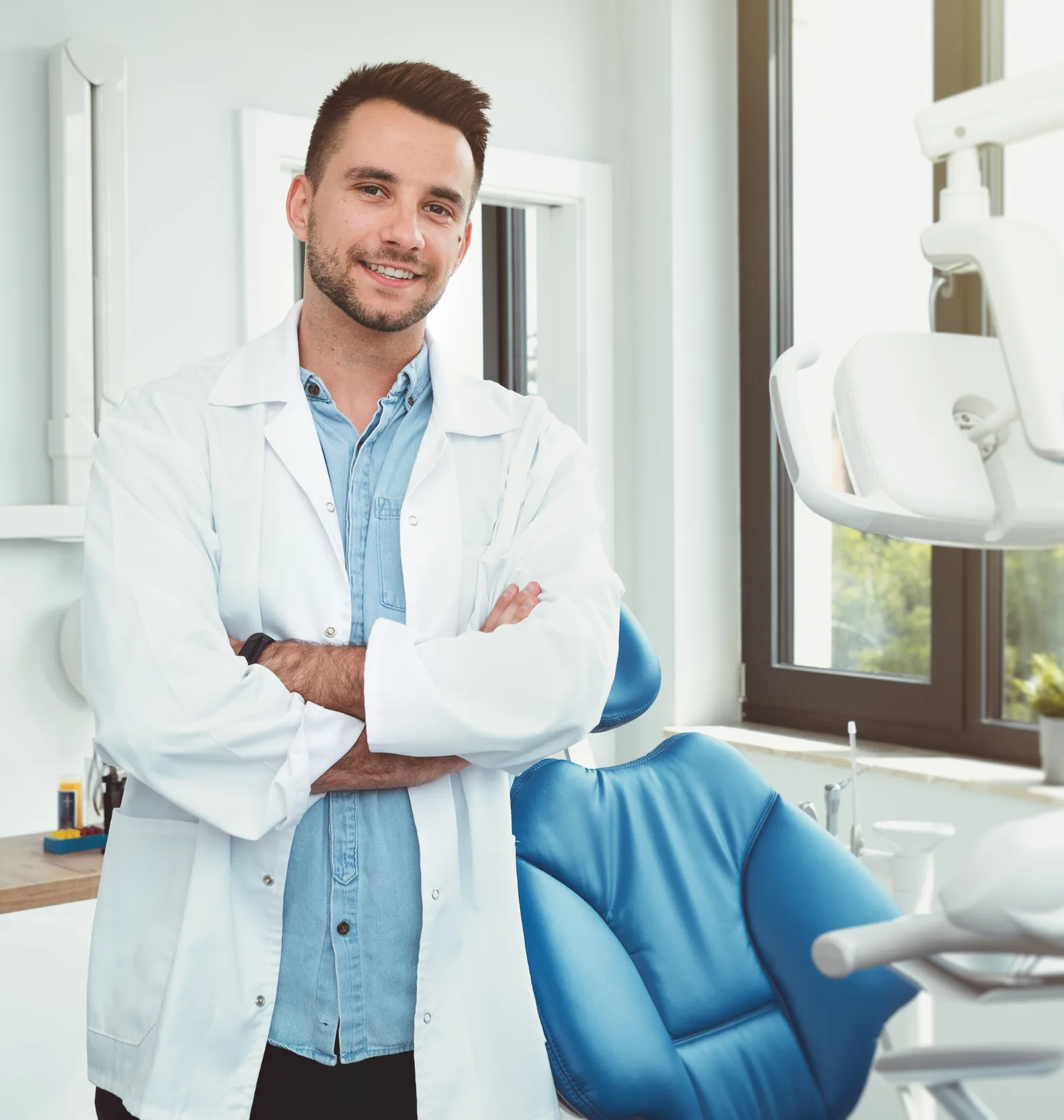 A dentist standing beside the treatment chair in a dental exam room