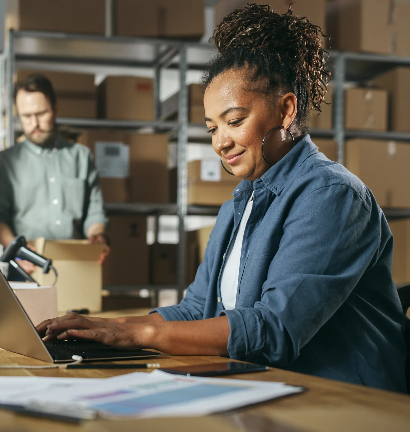 An ecommerce business owner working on a laptop in a fulfillment warehouse