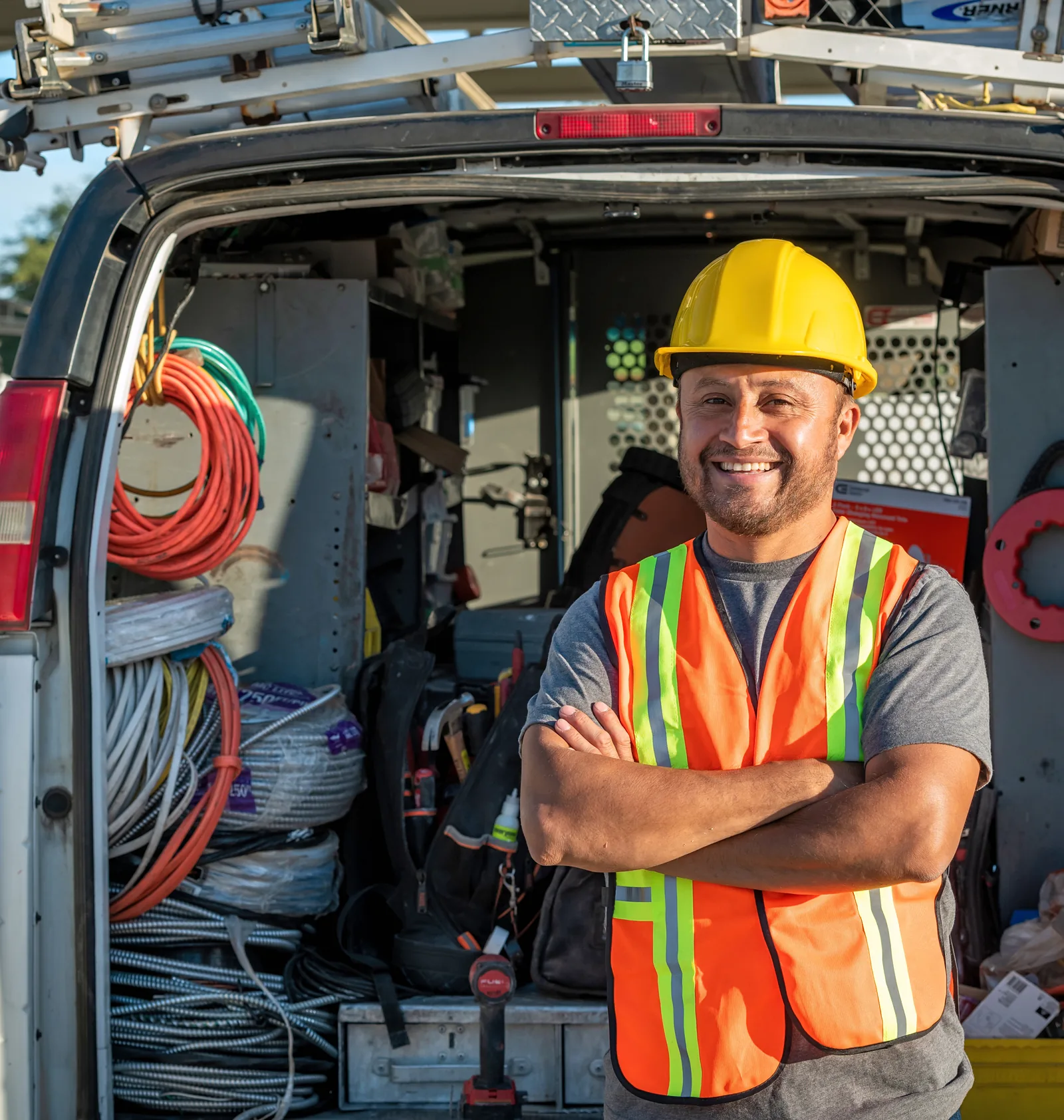 An electrician standing in front of his service van loaded with wiring and tools