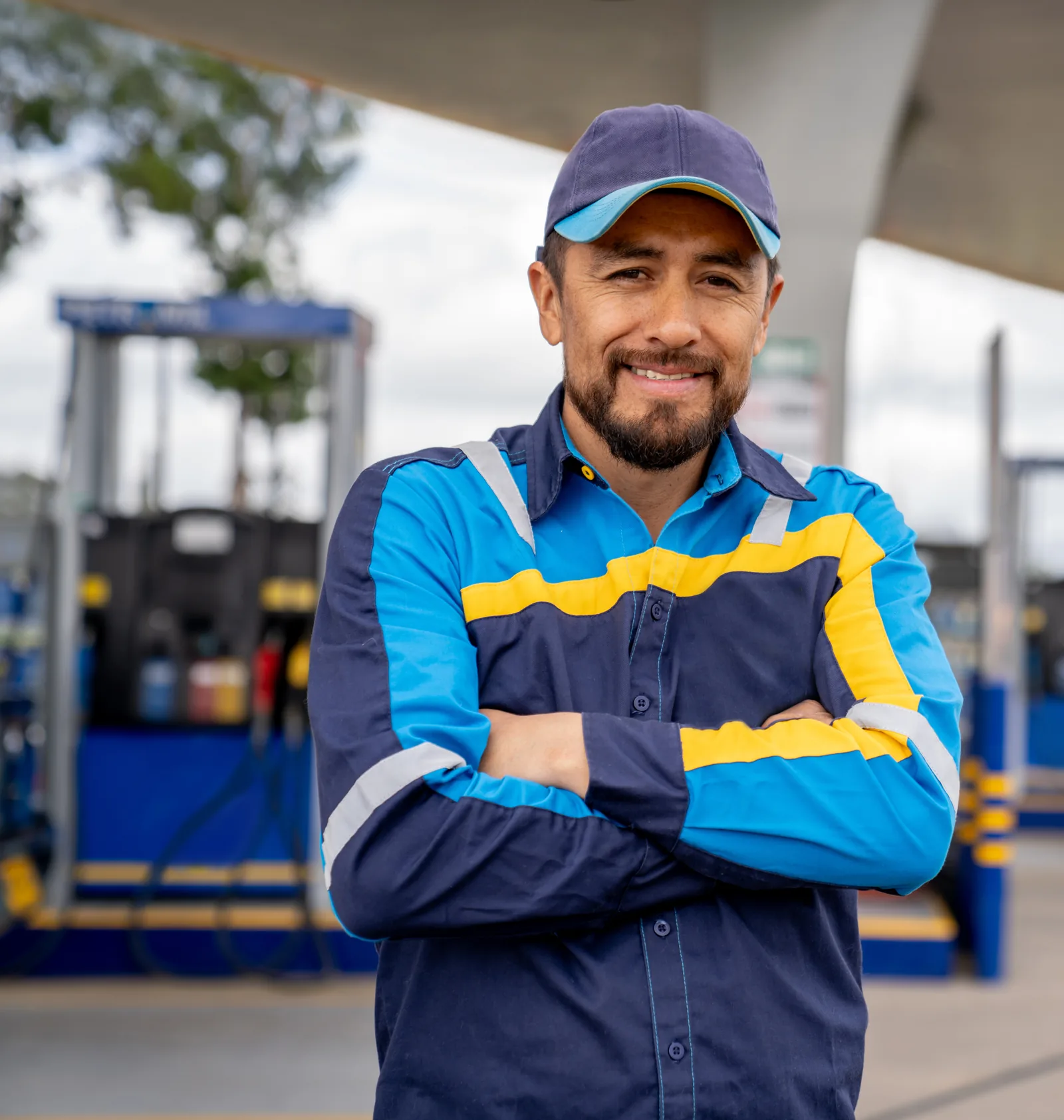 A gas station attendant standing at the fuel pumps