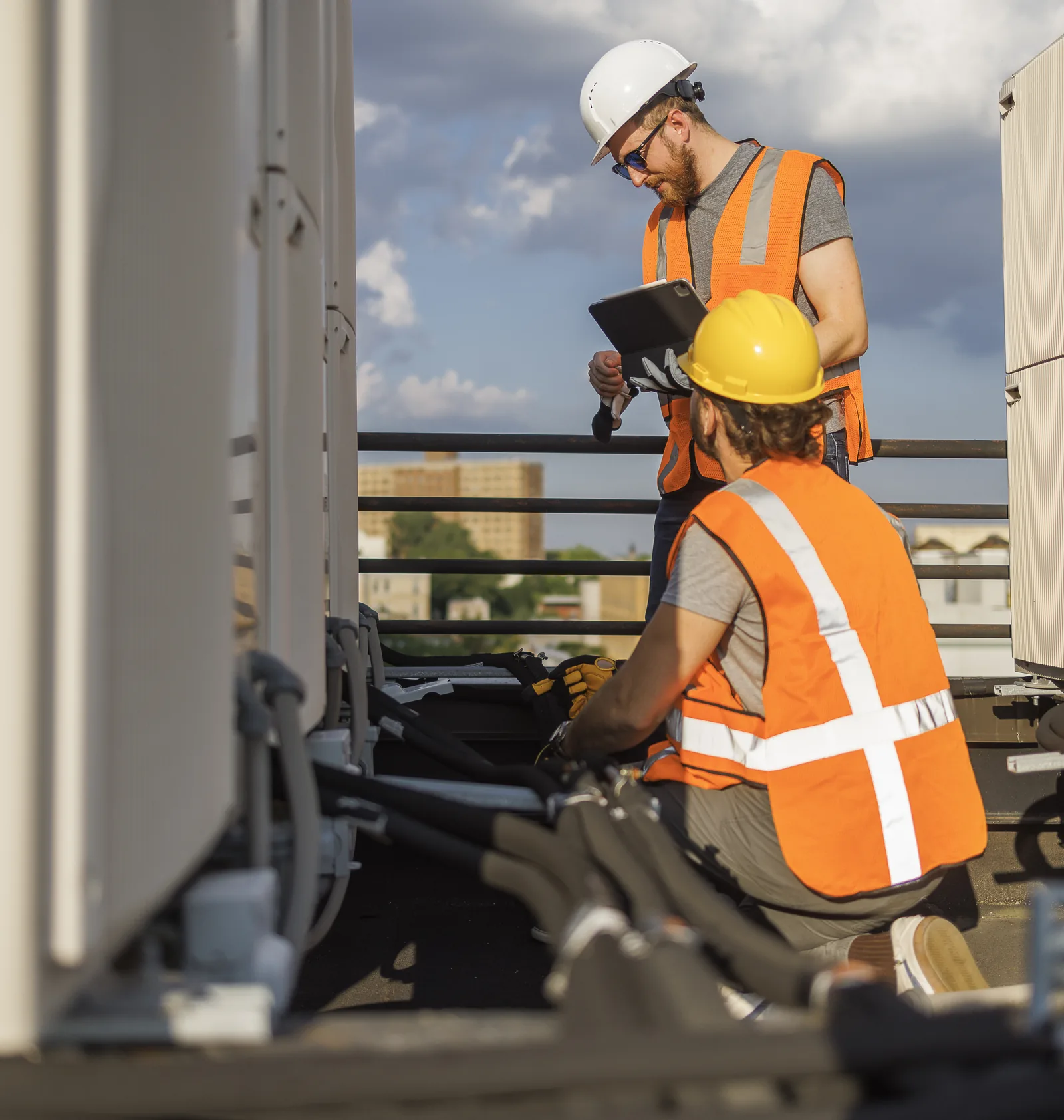 Two HVAC technicians servicing a rooftop unit
