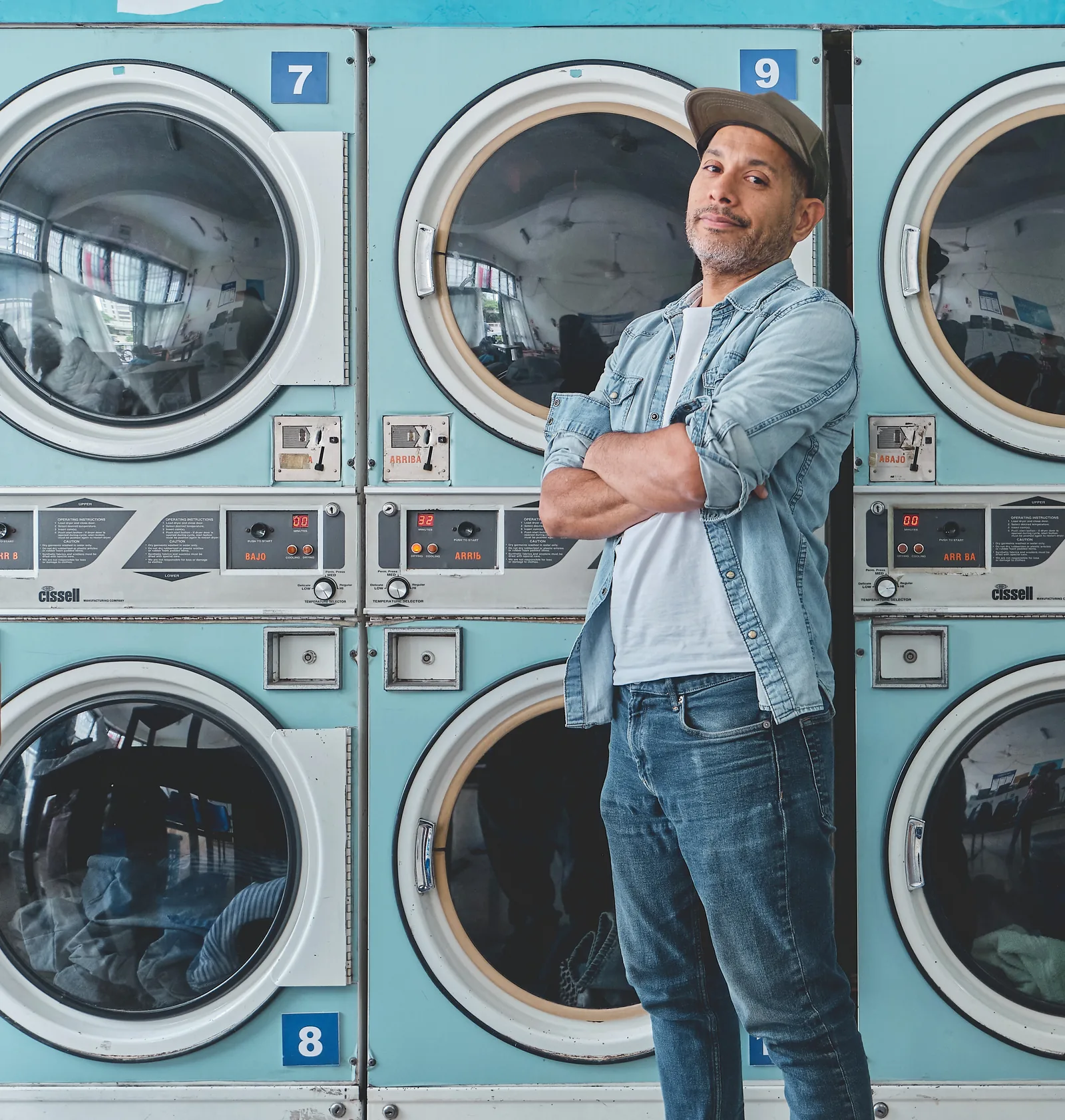 A laundromat owner standing among rows of washing machines