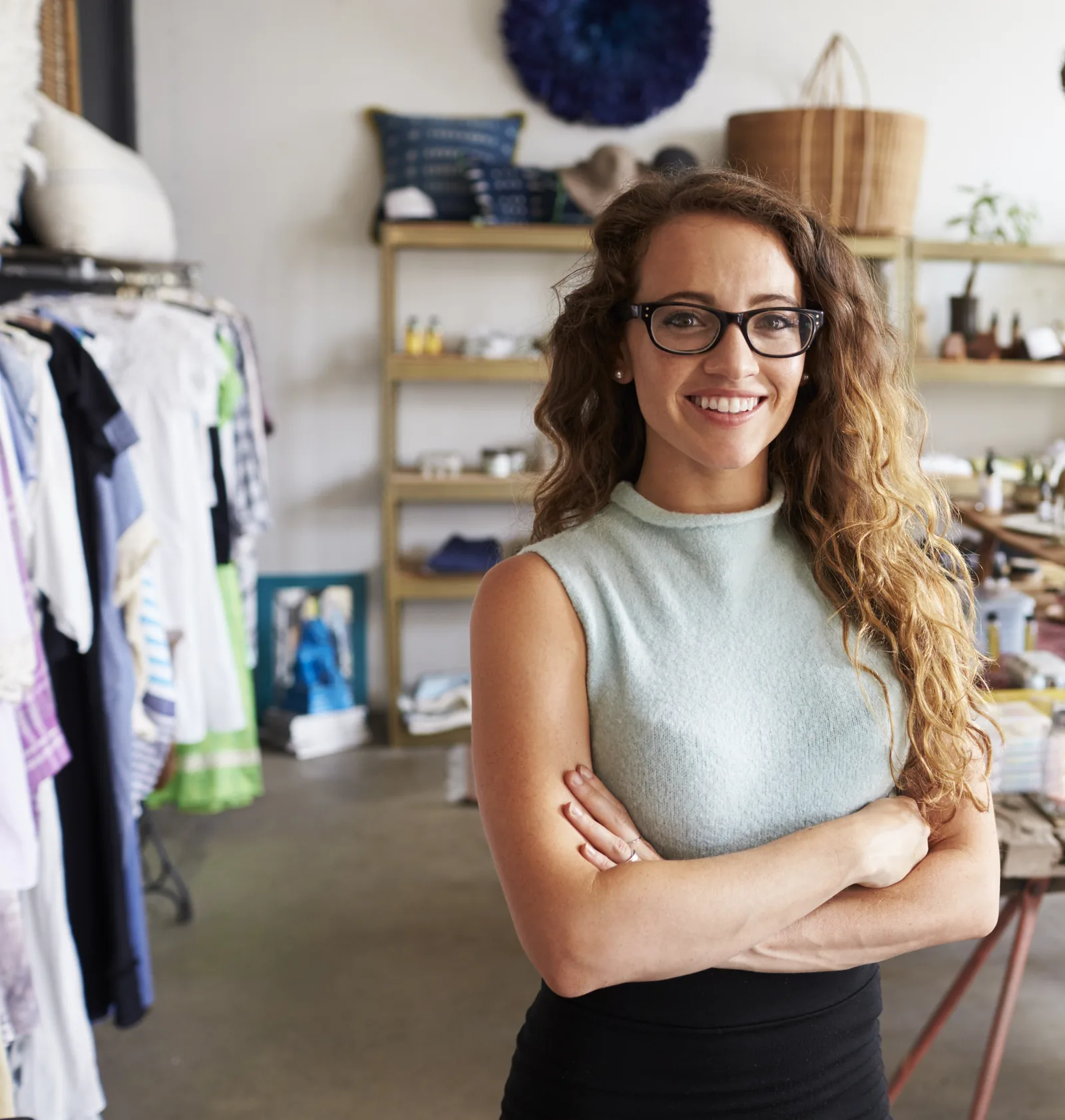 A boutique shop owner standing among clothing racks in her store