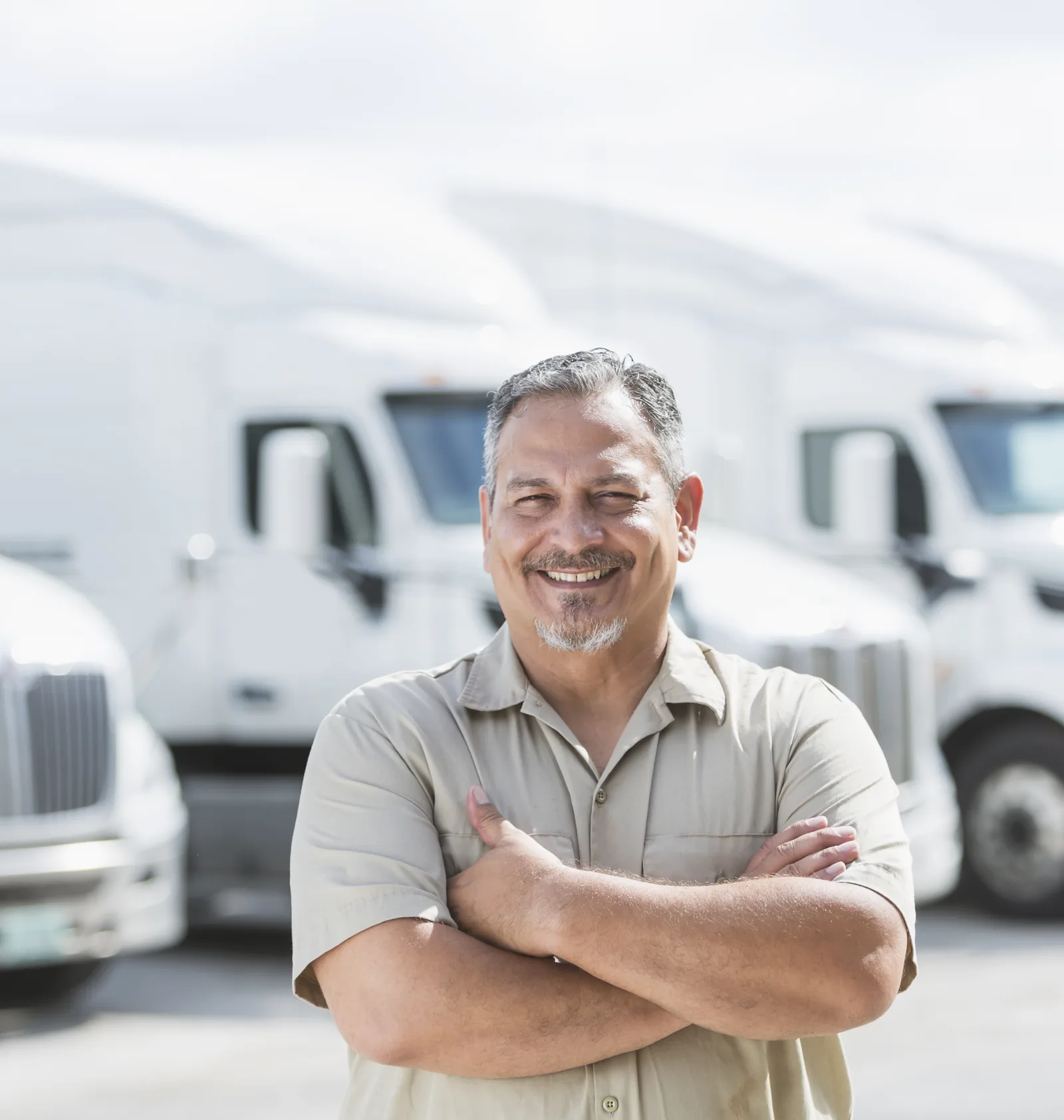 A trucking company owner standing in front of his fleet of semi trucks