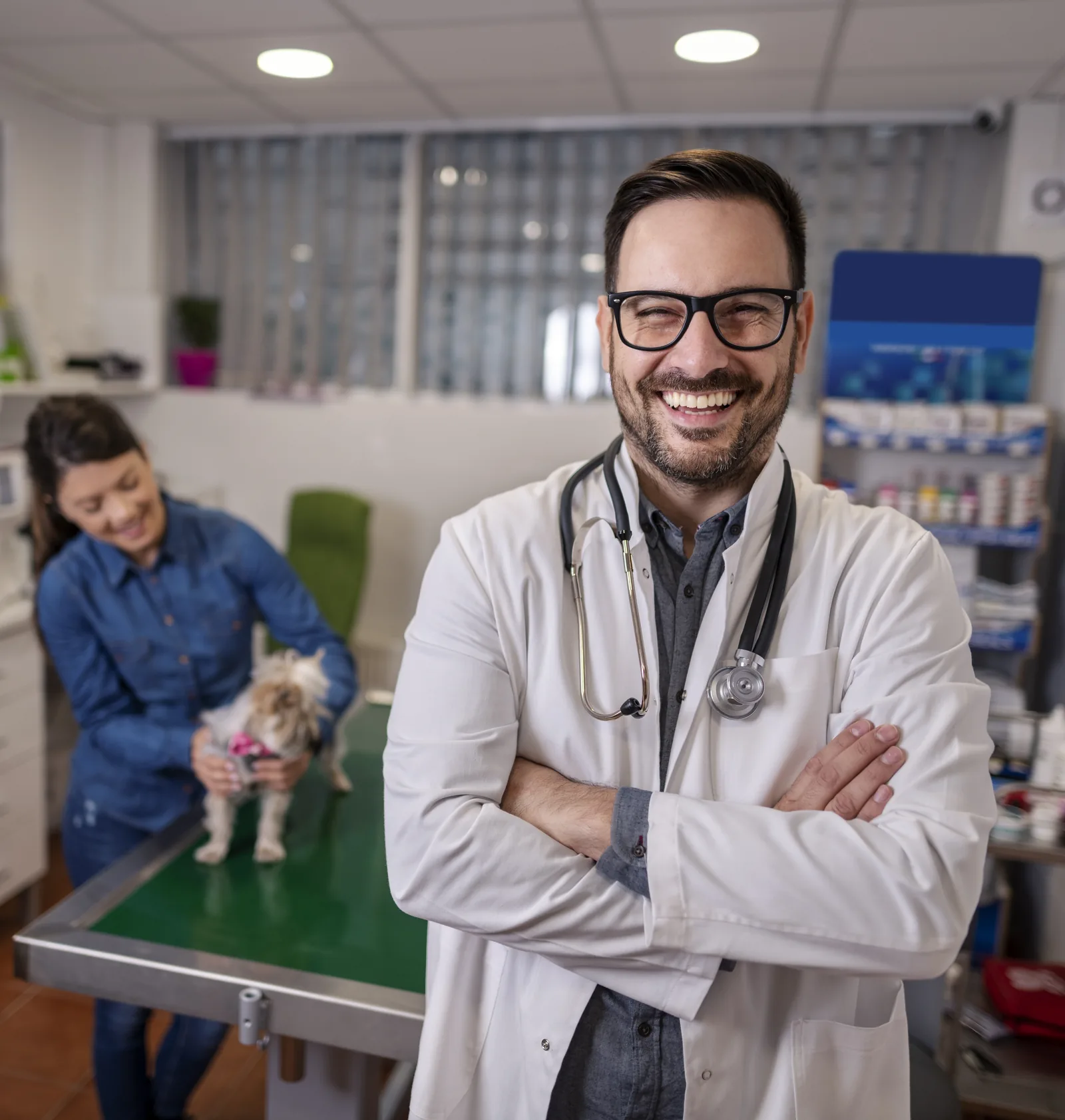 A veterinarian in his clinic with a client and her dog in the background